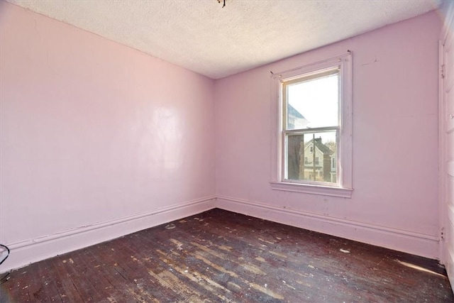 unfurnished room featuring a textured ceiling, baseboards, and hardwood / wood-style flooring