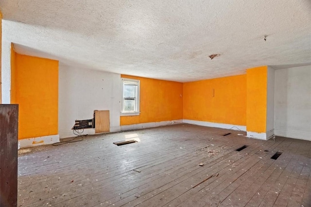 spare room featuring baseboards, a textured ceiling, and hardwood / wood-style flooring