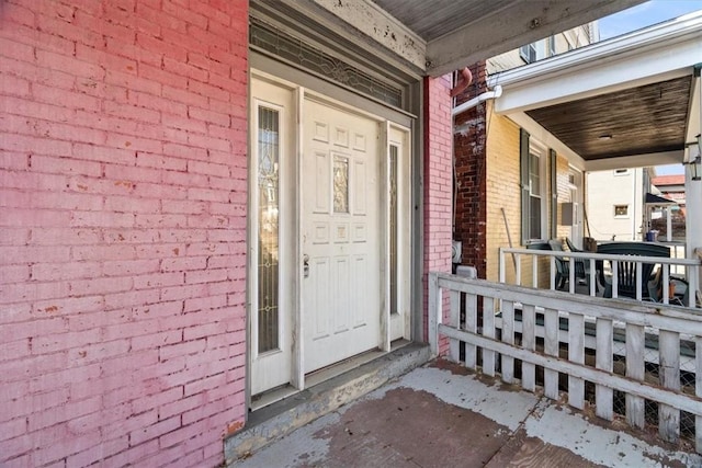 entrance to property with a porch and brick siding