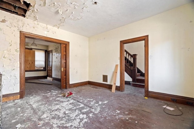 unfurnished room with stairway, baseboards, and visible vents