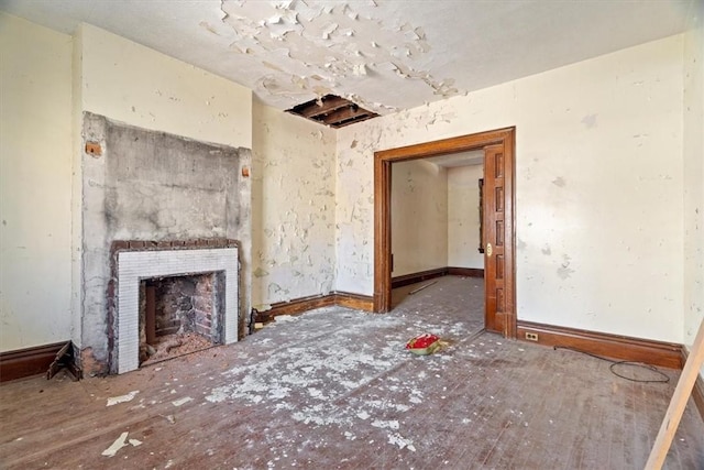 unfurnished living room with baseboards and a fireplace