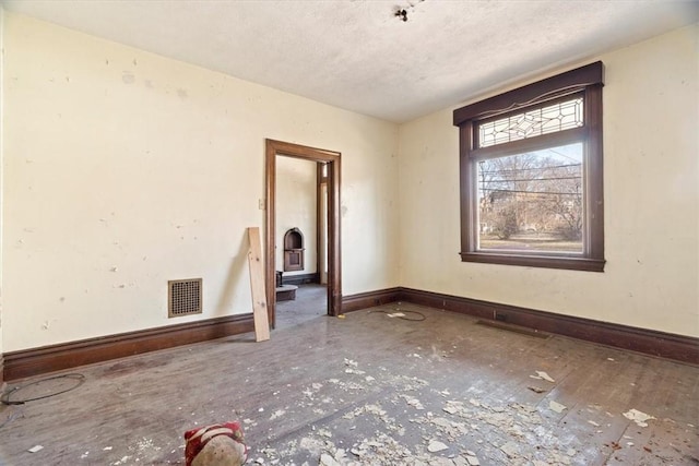 unfurnished room featuring baseboards, visible vents, and a textured ceiling