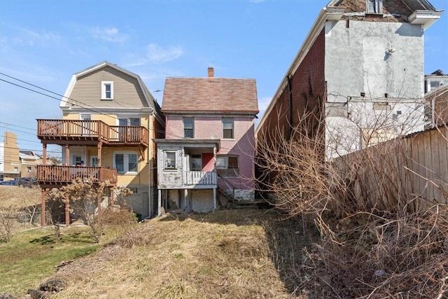 rear view of property with a gambrel roof, a lawn, and fence