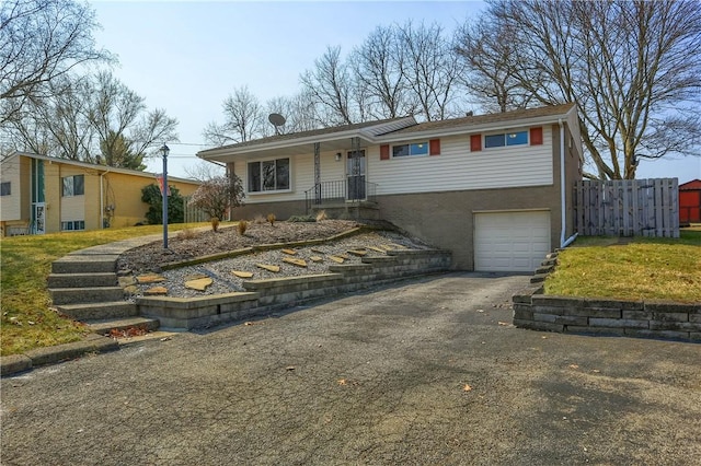 ranch-style home with aphalt driveway, a garage, and fence