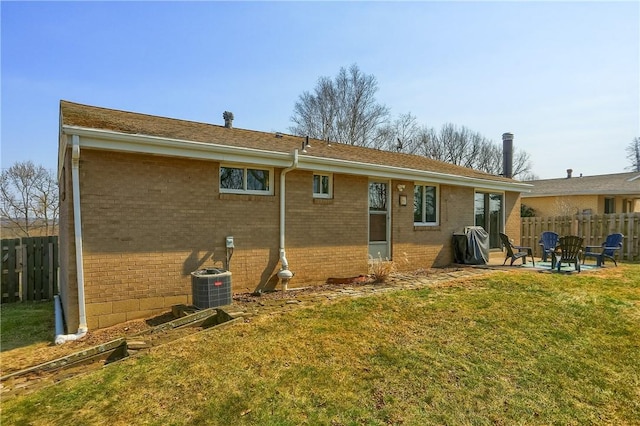 back of house featuring a yard, fence, brick siding, and cooling unit