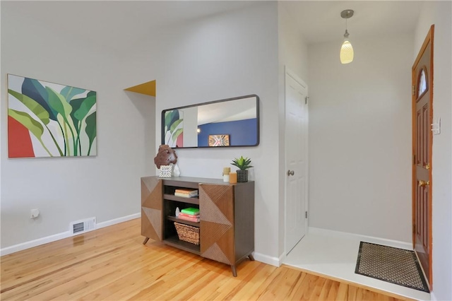 entryway with wood finished floors, visible vents, and baseboards