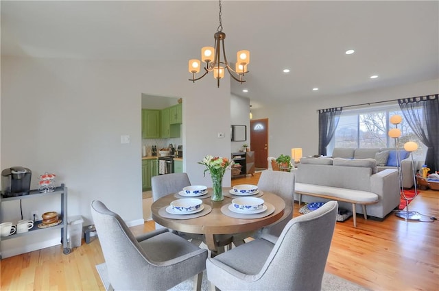 dining area featuring recessed lighting, light wood-style flooring, an inviting chandelier, and vaulted ceiling