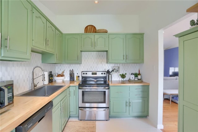 kitchen featuring a sink, backsplash, light countertops, stainless steel appliances, and green cabinetry