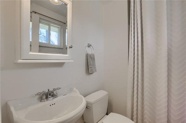 bathroom featuring a sink, curtained shower, and toilet