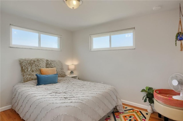 bedroom featuring multiple windows, baseboards, and light wood-type flooring