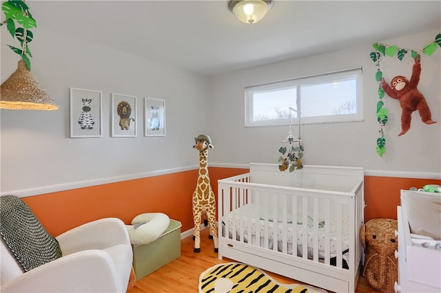 bedroom with a crib and wood finished floors