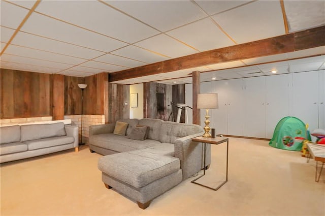 carpeted living room featuring wooden walls and a paneled ceiling