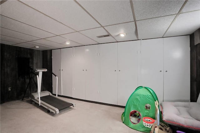 exercise room featuring a paneled ceiling, visible vents, and carpet floors