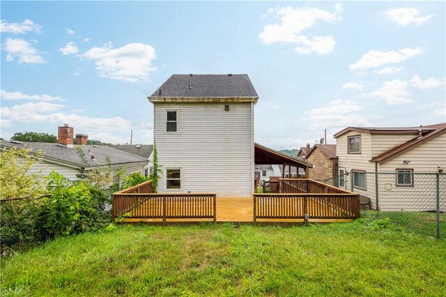 rear view of house featuring a lawn, a deck, and fence