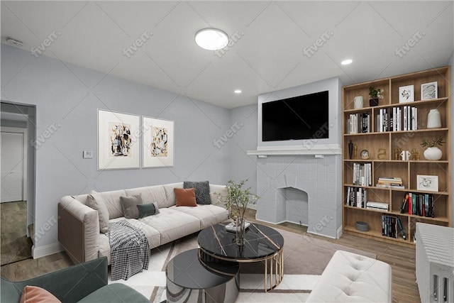 living room featuring recessed lighting, wood finished floors, and a tiled fireplace