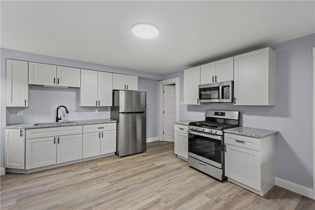 kitchen featuring appliances with stainless steel finishes, white cabinetry, and a sink