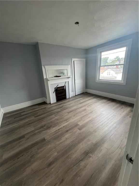 unfurnished living room with baseboards, dark wood-style floors, and a fireplace