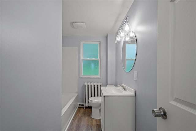 bathroom featuring vanity, toilet, radiator heating unit, and wood finished floors