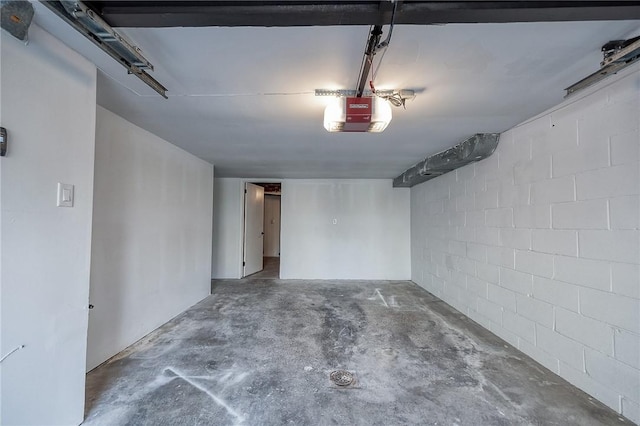 garage featuring concrete block wall and a garage door opener