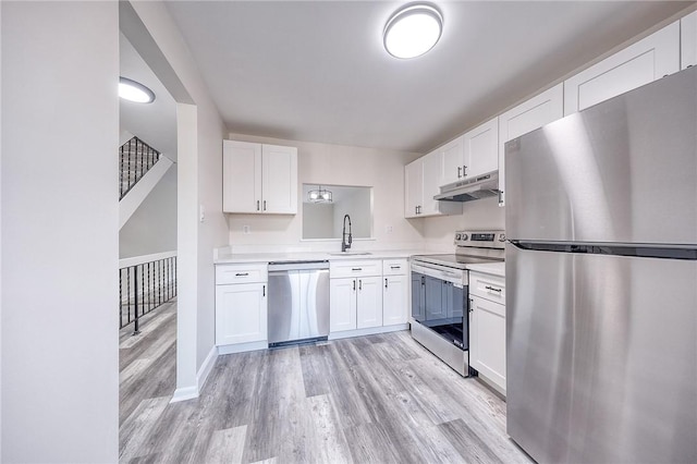 kitchen featuring under cabinet range hood, a sink, appliances with stainless steel finishes, white cabinets, and light countertops