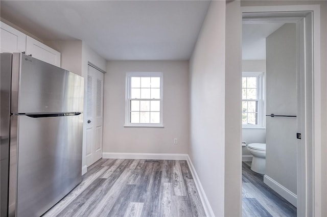 kitchen with white cabinets, light wood-type flooring, freestanding refrigerator, and baseboards