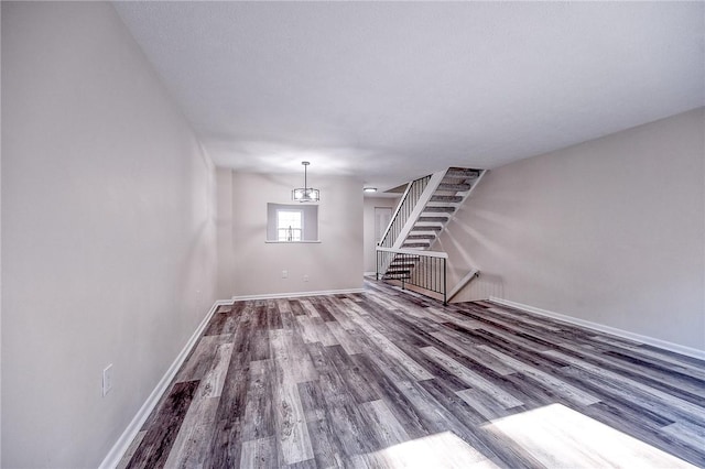 unfurnished living room featuring baseboards, wood finished floors, and stairs