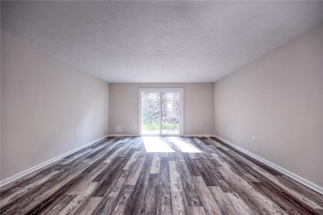 empty room featuring a textured ceiling, dark wood-type flooring, and baseboards