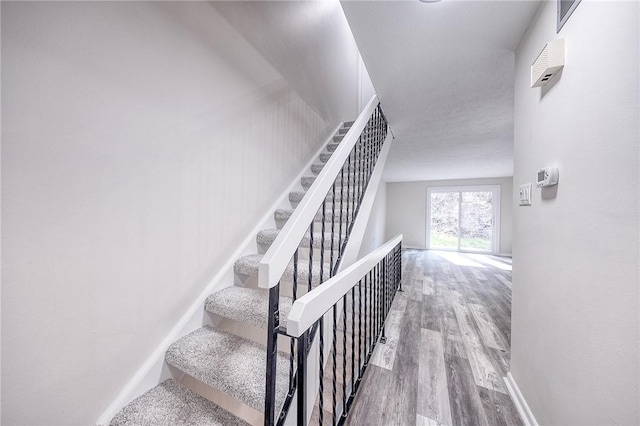 stairway with wood finished floors and baseboards