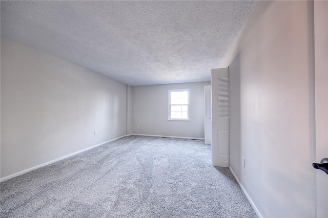 carpeted empty room featuring baseboards and a textured ceiling