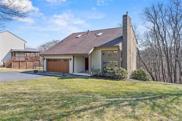 view of front of house featuring aphalt driveway, roof with shingles, a front yard, an attached garage, and a chimney