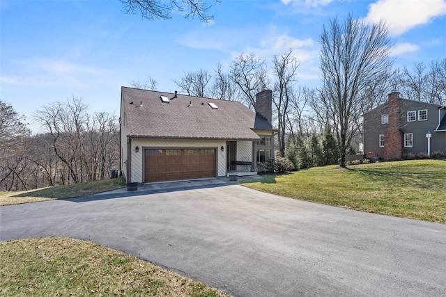 view of front facade featuring an attached garage, a front yard, a chimney, and driveway