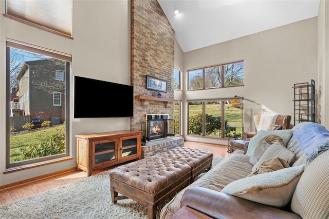 living room with baseboards, high vaulted ceiling, a brick fireplace, and wood finished floors