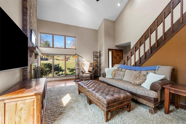 living room featuring stairway, a brick fireplace, wood finished floors, and high vaulted ceiling