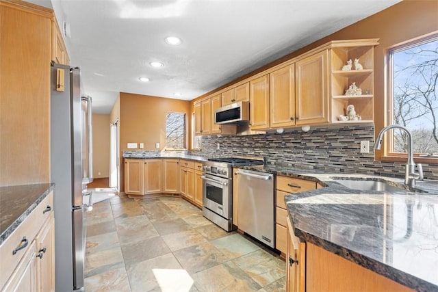 kitchen with a sink, open shelves, tasteful backsplash, dark stone counters, and appliances with stainless steel finishes