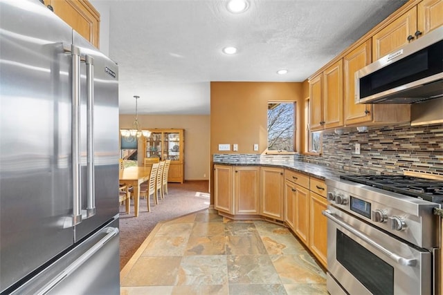 kitchen featuring high end appliances, recessed lighting, light colored carpet, tasteful backsplash, and a chandelier