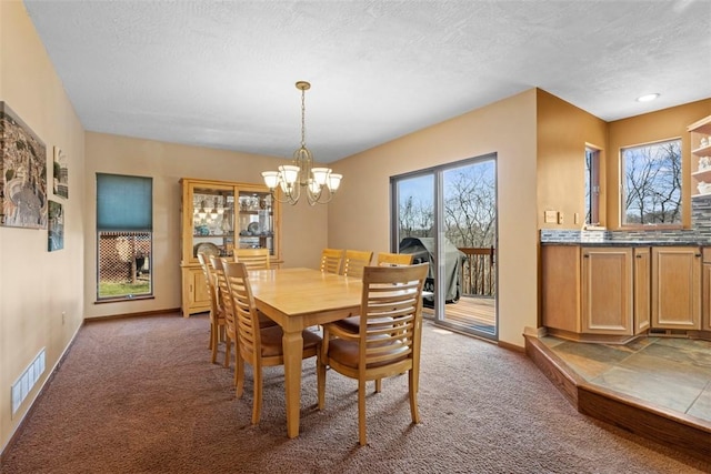 carpeted dining space with visible vents, a textured ceiling, baseboards, and an inviting chandelier