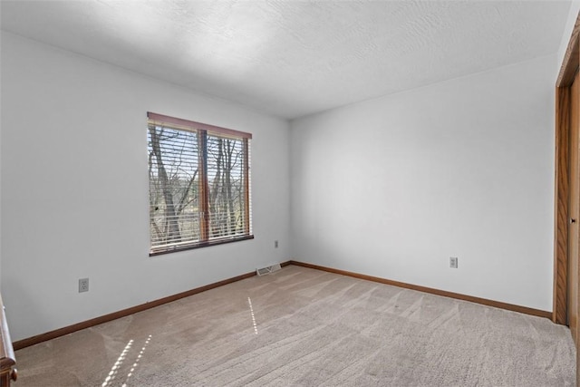 carpeted empty room with visible vents, a textured ceiling, and baseboards