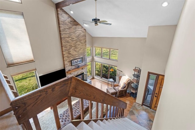 staircase featuring plenty of natural light, beamed ceiling, a brick fireplace, and high vaulted ceiling