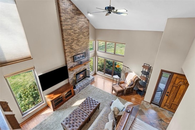 living area with a brick fireplace, a healthy amount of sunlight, and high vaulted ceiling