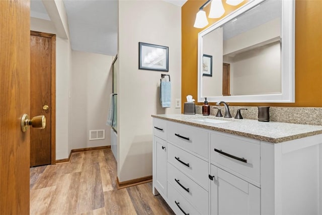 bathroom with visible vents, baseboards, bathtub / shower combination, wood finished floors, and vanity