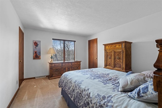 bedroom with baseboards, light colored carpet, visible vents, and a textured ceiling