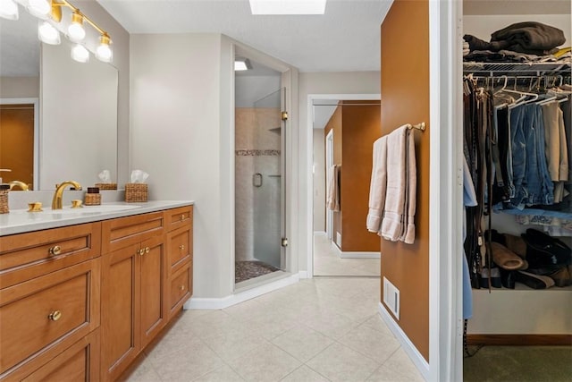 bathroom featuring a walk in closet, vanity, a skylight, and a shower stall