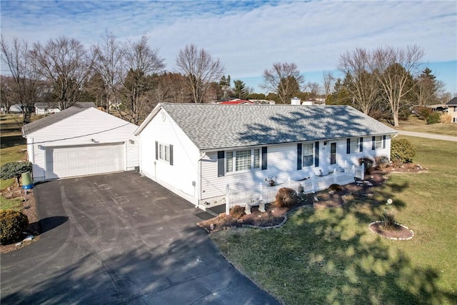 ranch-style house with an outbuilding, a garage, a shingled roof, and a front yard