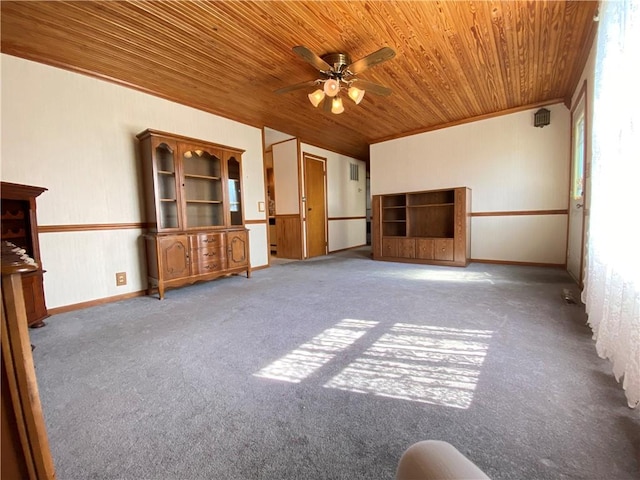 unfurnished living room with baseboards, ceiling fan, crown molding, wooden ceiling, and carpet flooring