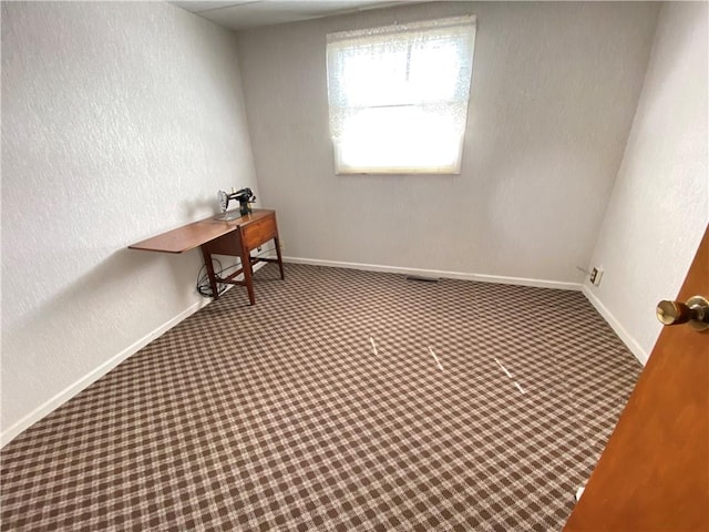 unfurnished office with a textured wall, baseboards, and carpet floors