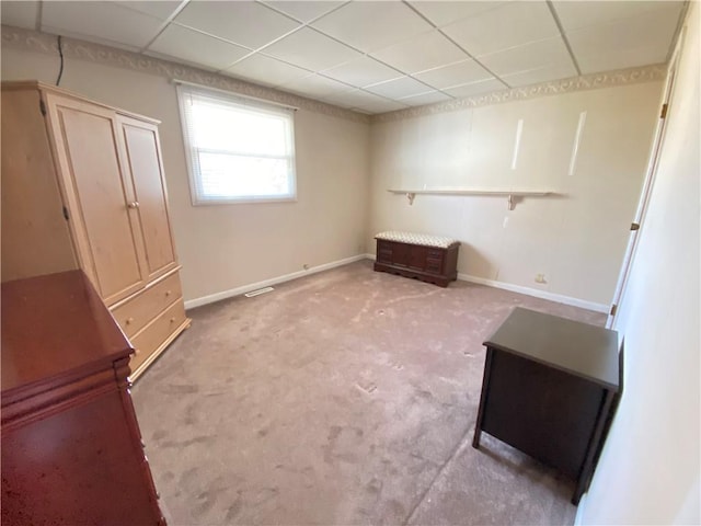 unfurnished bedroom featuring light carpet, a paneled ceiling, and baseboards