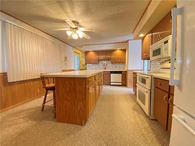 kitchen with decorative backsplash, white appliances, wooden walls, and a breakfast bar area