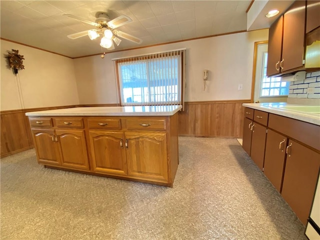 kitchen with light countertops, wooden walls, crown molding, and a wainscoted wall