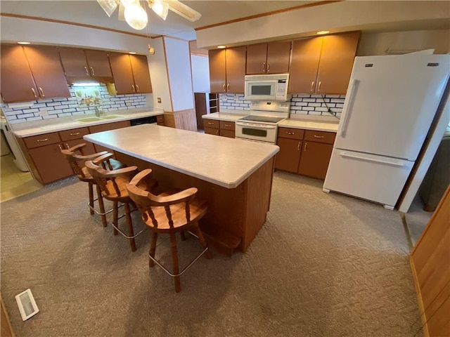 kitchen featuring visible vents, backsplash, light countertops, white appliances, and a sink