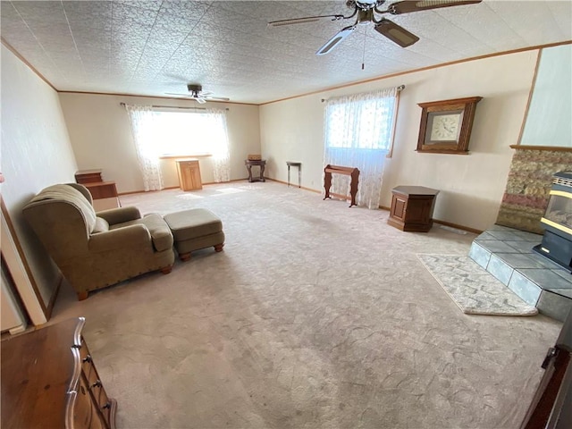 living area with baseboards, carpet, ceiling fan, and crown molding